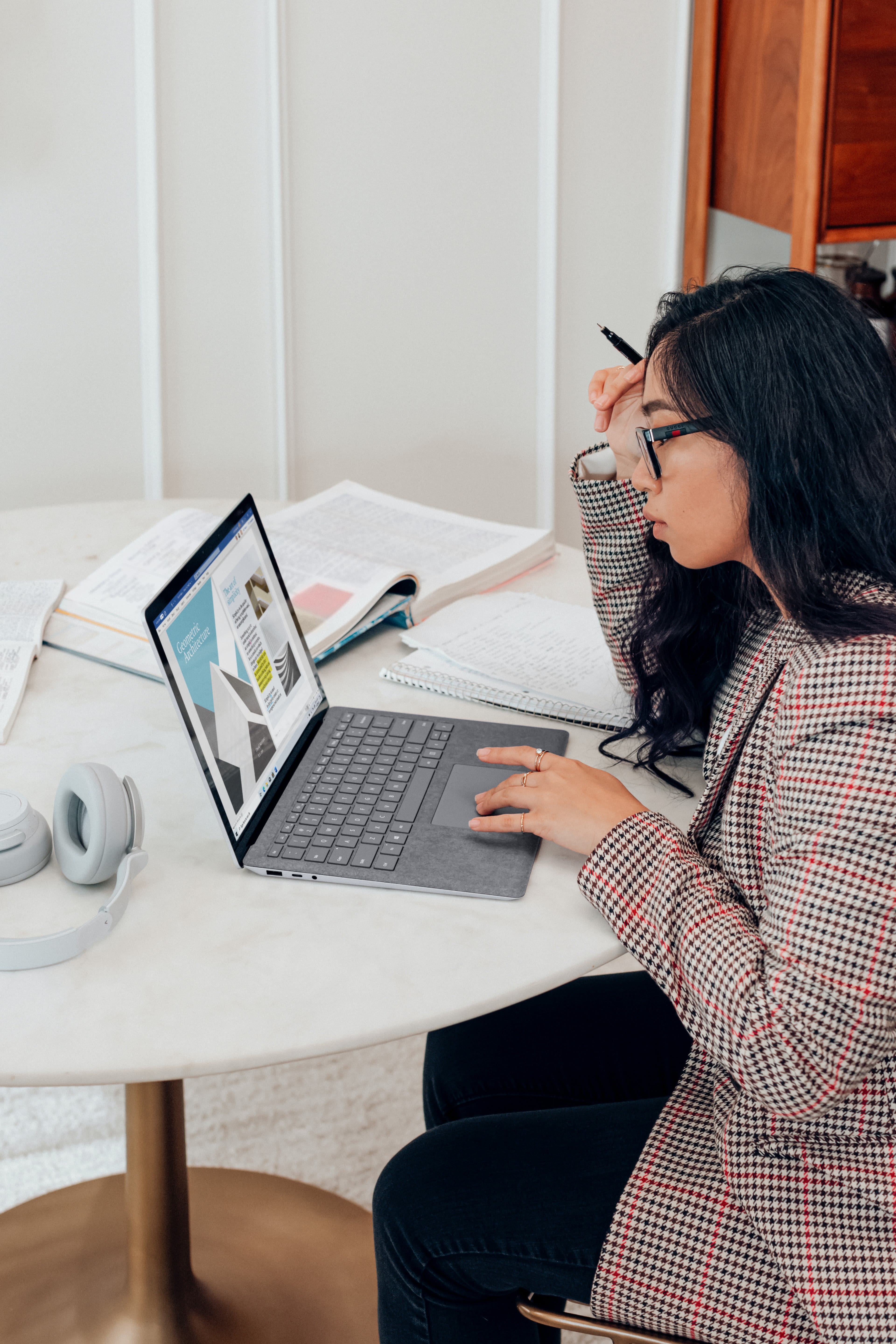 woman in red and white plaid dress shirt using microsoft surface laptop 