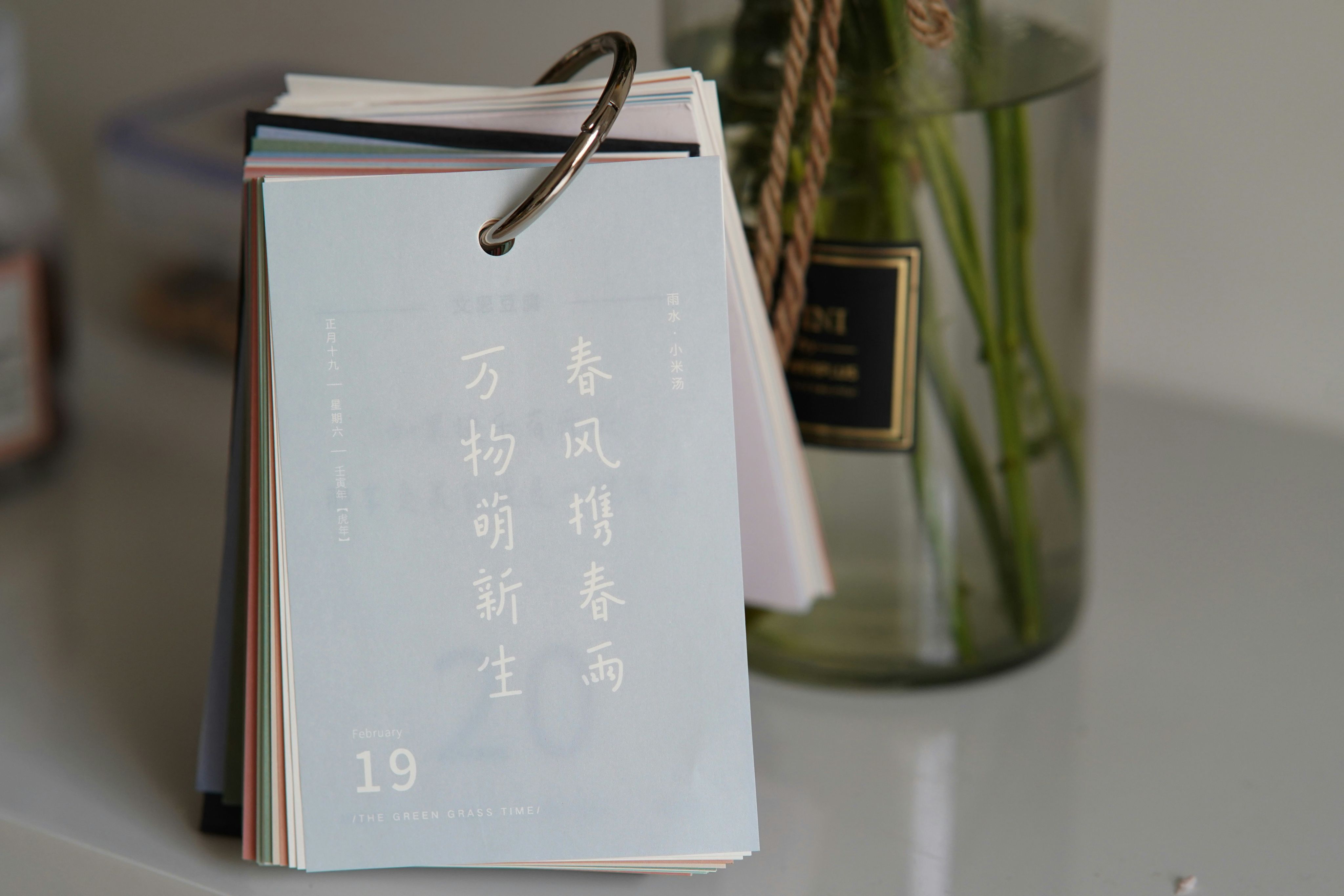 A flip calendar with chinese text and a vase.