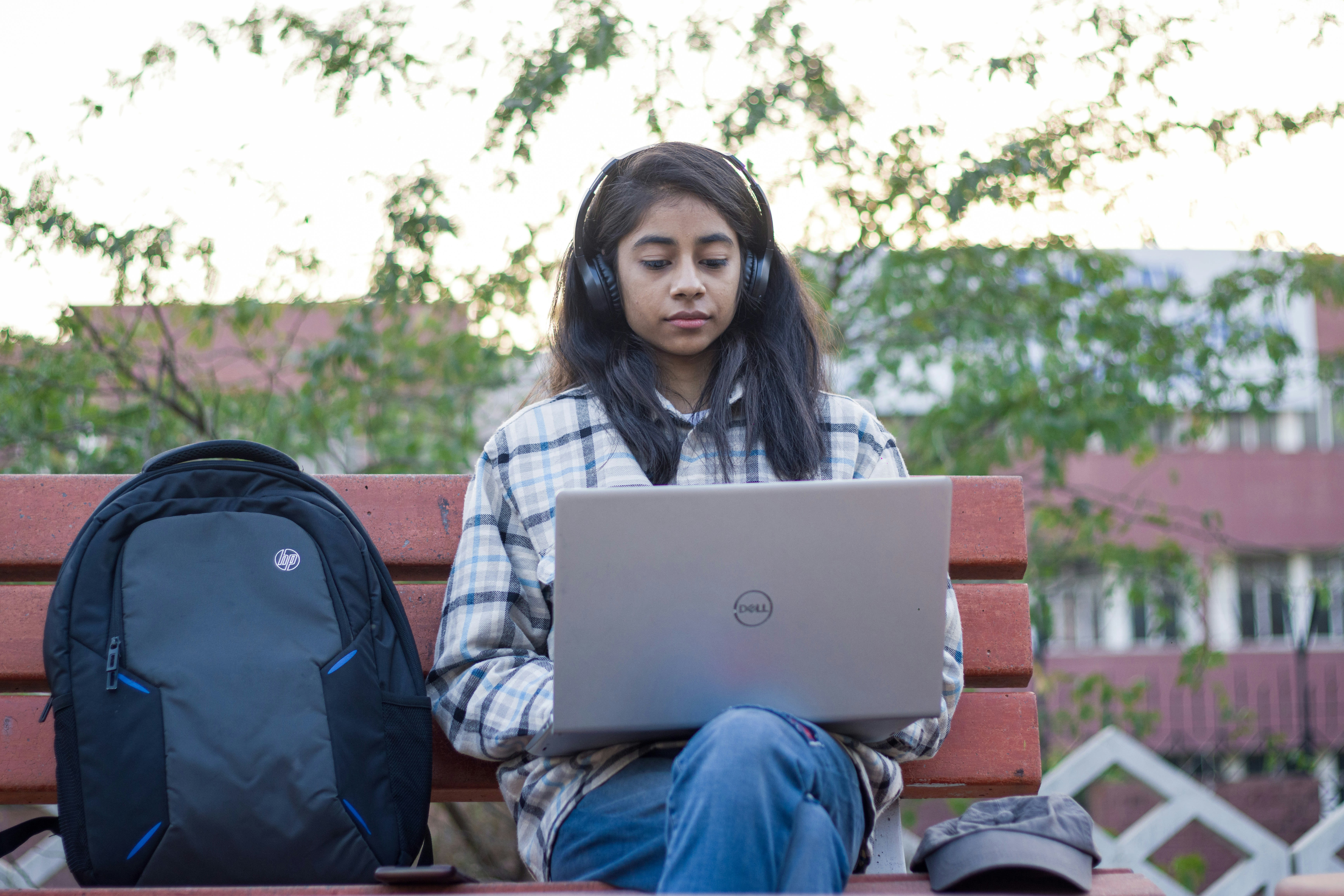 a woman sitting on a bench using a laptop computer
