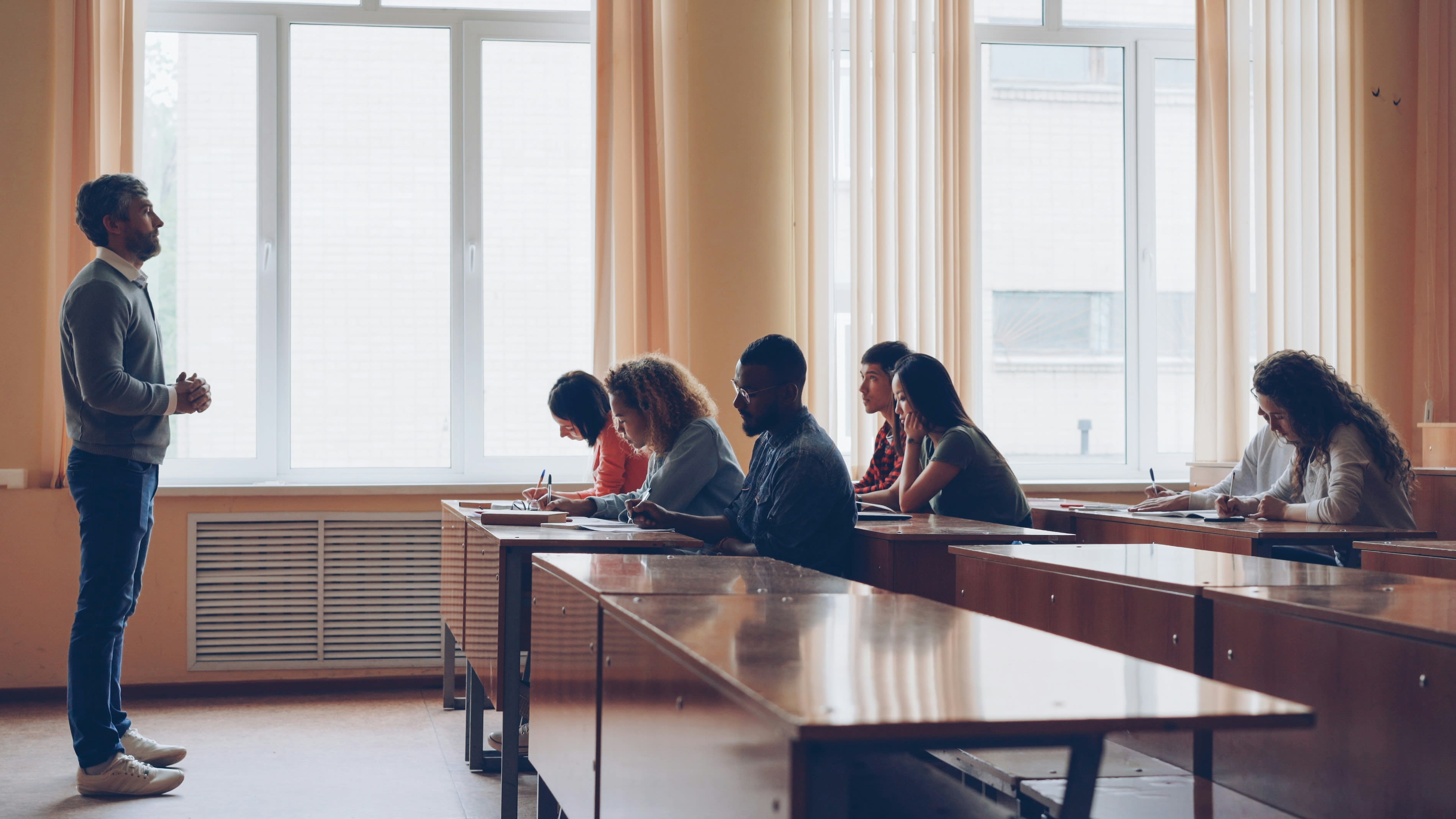 Teacher lecturing students in a classroom setting.